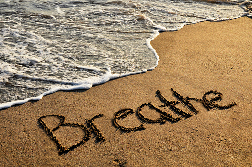 Word breathe on sunset beach