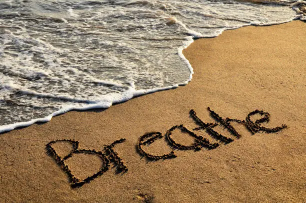 Word breathe on sunset beach