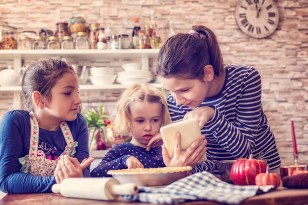 istock Young Girls Preparing Pumpkin Pie for the Holidays 821593788