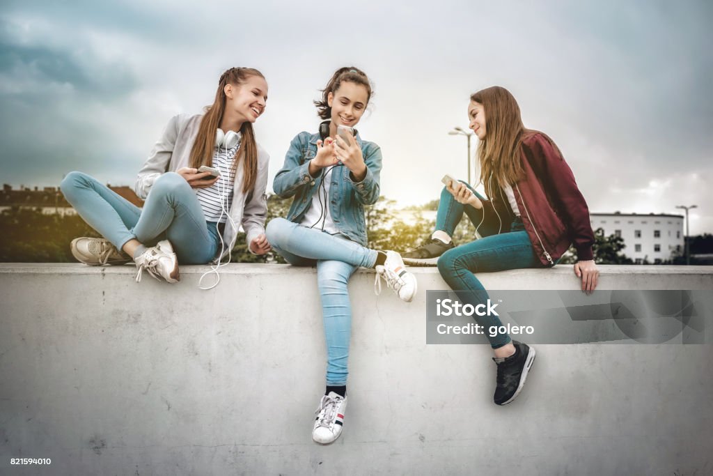 drei Mädchen im Teenageralter mit Smartphones auf Betonwand - Lizenzfrei Teenager-Alter Stock-Foto