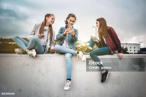 Drei Mädchen Im Teenageralter Mit Smartphones Auf Betonwand Stockfoto und mehr Bilder von Teenager-Alter