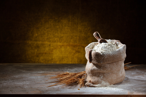 Closeup shot of flour in sack on rustic wooden table.