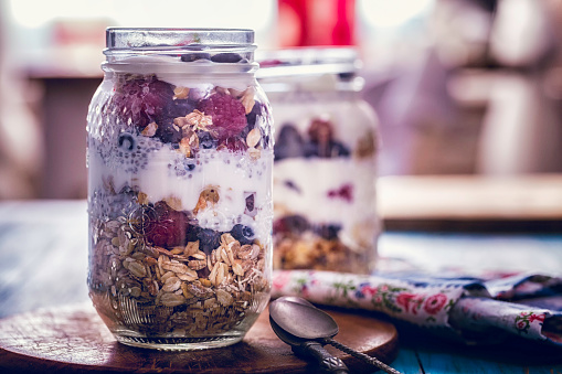 Granola with yogurt in glass served with fresh raspberry, blueberry and honey. Homemade oatmeal muesli. Vegetarian breakfast, healthy eating concept. Selective focus.