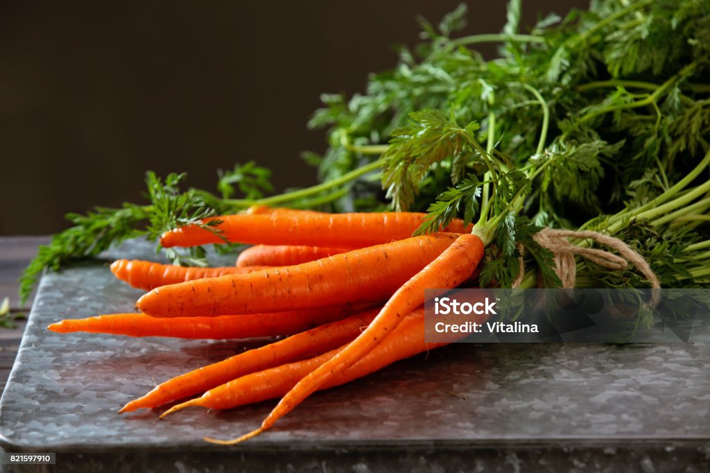 Heap of ripe carrots. Heap of ripe carrots with leaves on dark rustic table. Carrot Stock Photo