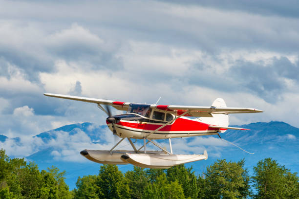 A small red and white float plane taking off of water in a wilderness setting.