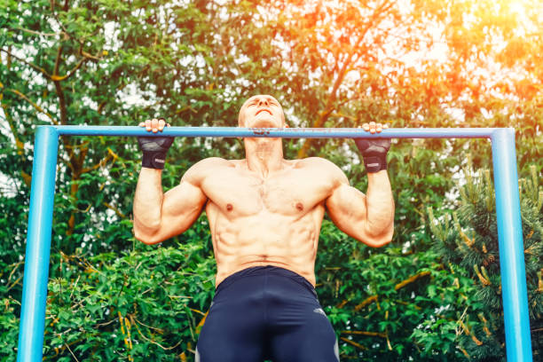 istock Closeup of strong bald athlete doing pull-up on horizontal bar. front view 821612334
