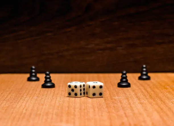 Photo of Black pawns and dice on a wooden background