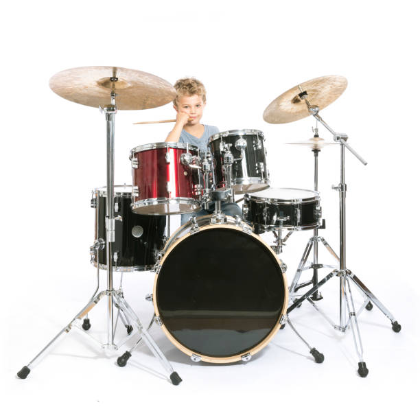 istock young caucasian boy plays drums in studio against white background 821618174