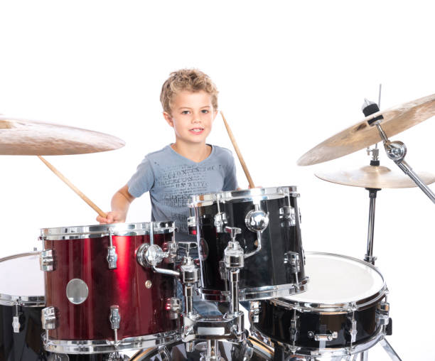istock young caucasian boy plays drums in studio against white background 821618184