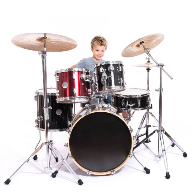 istock young caucasian boy plays drums in studio against white background 821618192