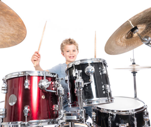 istock young caucasian boy plays drums in studio against white background 821618198
