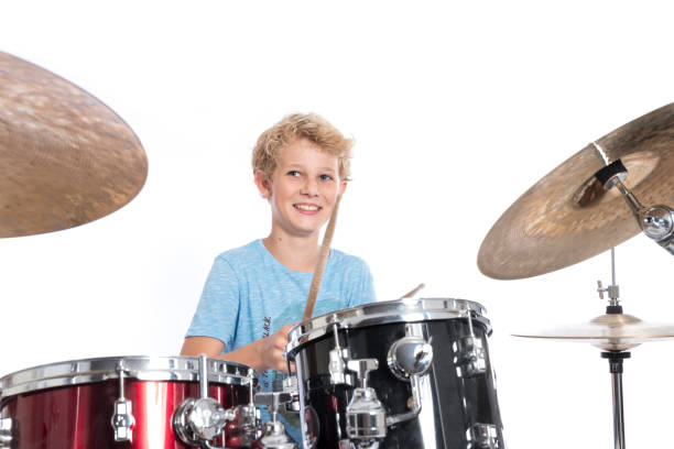 istock blond teen boy plays drums at drumkit in studio against white background 821618222
