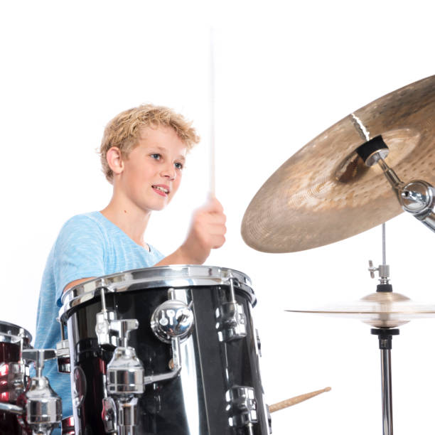 istock blond teen boy plays drums at drumkit in studio against white background 821618228