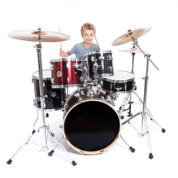 istock young caucasian boy plays drums in studio against white background 821618240