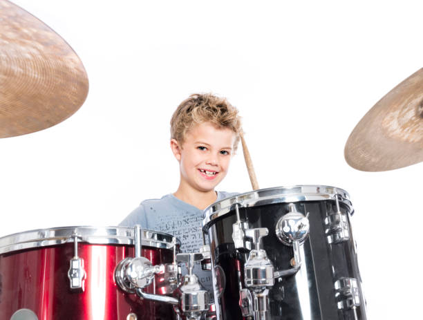 istock young caucasian boy plays drums in studio against white background 821618254