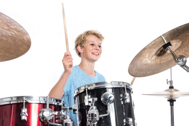 istock blond teen boy plays drums at drumkit in studio against white background 821618262
