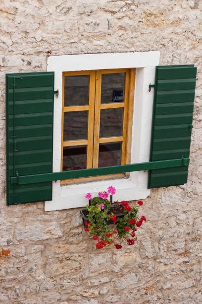 istock wooden window with green shutters and flowers 821618704