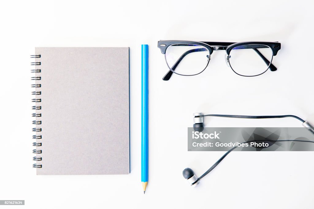 Top view of business working place with notepad,modern glasses,earphone on white table,flatlay concept. Top - Garment Stock Photo