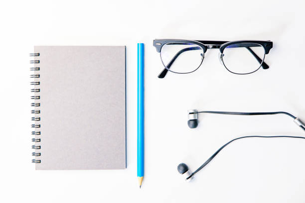 Top view of business working place with notepad,modern glasses,earphone on white table,flatlay concept. stock photo