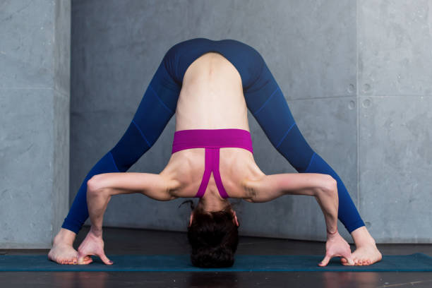 istock Full-length front view of sporty young woman practicing yoga doing standing straddle forward bend pose, Prasarita Padottanasana, working-out indoors 821628056