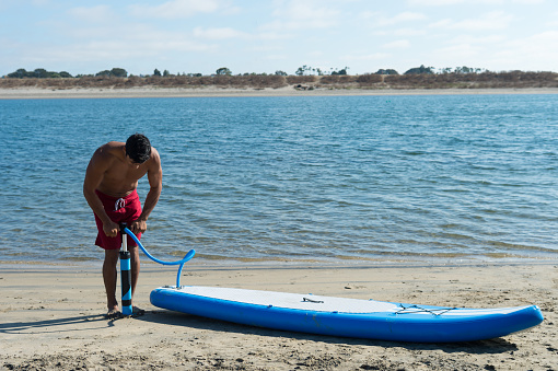 Man Pumping an inflatable Stand Up Paddle Board.