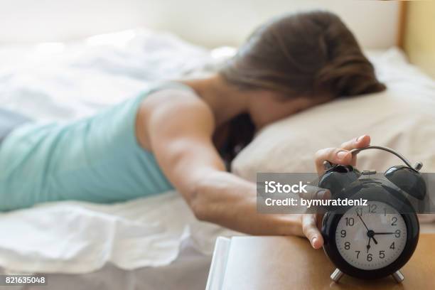 Wake Up Of A Girl Stopping Alarm Clock Stock Photo - Download Image Now - Alarm Clock, Sleeping, Waking up