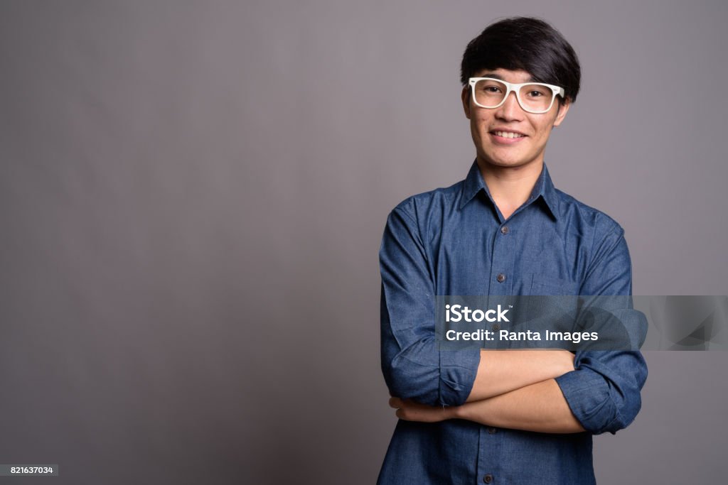 Studio shot of young Asian man wearing smart casual clothes and eyeglasses against gray background Studio shot of young Asian man wearing smart casual clothes and eyeglasses against gray background horizontal shot Portrait Stock Photo