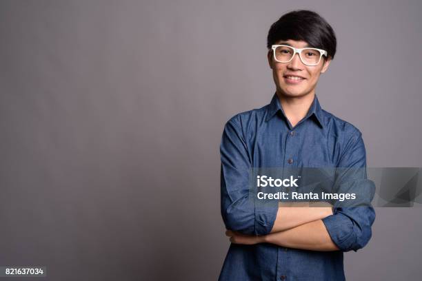 Studio Shot Of Young Asian Man Wearing Smart Casual Clothes And Eyeglasses Against Gray Background Stock Photo - Download Image Now