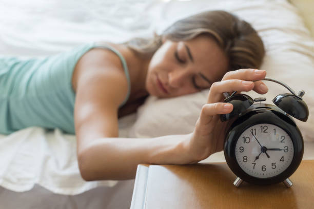 istock Sleepy young woman trying stop alarm clock 821637252