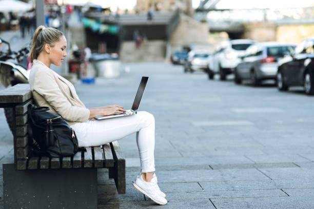istock Woman using laptop on the street 821639946