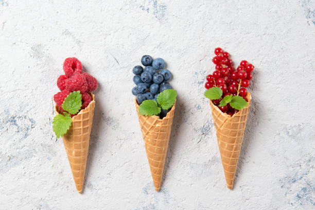 istock Fresh berries in waffle cones on stone background, raspberry, blueberry and redcurrant with mint leaves, top view 821658970
