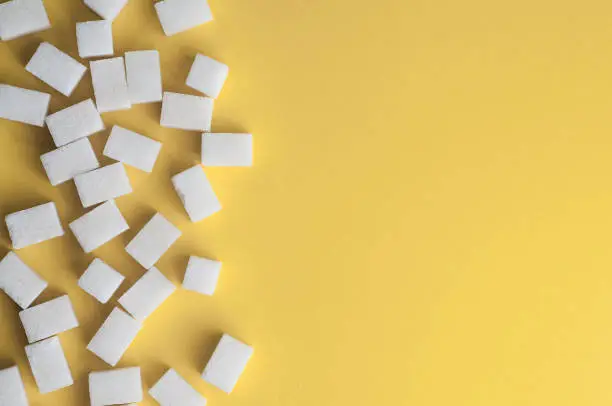 White sugar on yellow background. Cubes sugar with copy space. Top view or flat lay