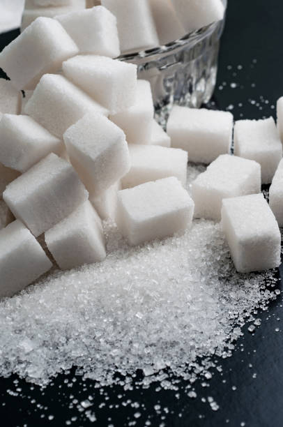 istock white granulated and refined sugar on black surface, close-up 821661468