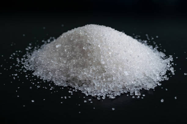 istock Heap of granulated white sugar on black surface 821661992