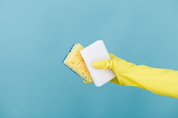 istock hand  in yellow glove holding sponge on blue background. cleaning 821666132