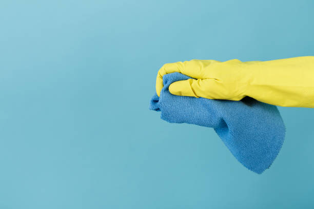 istock hand  in a rubber yellow glove holding sponge on blue background. 821666202