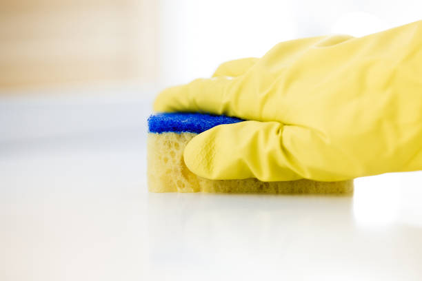 istock Female hand in rubber yellow glove cleans surface of table 821666314