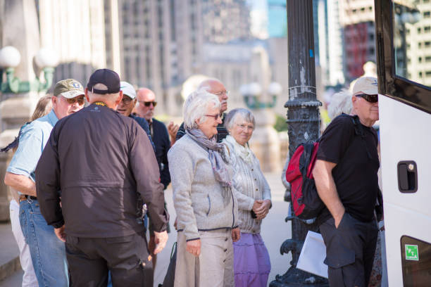Older tourists exploring Chicago by bus CHICAGO, IL, June 6, 2017: Older tourists smile and laugh as they board a tour bus downtown Chicago, in the Loop. Millions of people visit Chicago every year. millennium park stock pictures, royalty-free photos & images