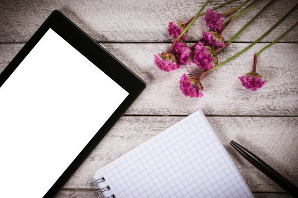 istock workspace with notebook and tablet.flowers on wooden background with copy space.  celebration template concept. 821668770