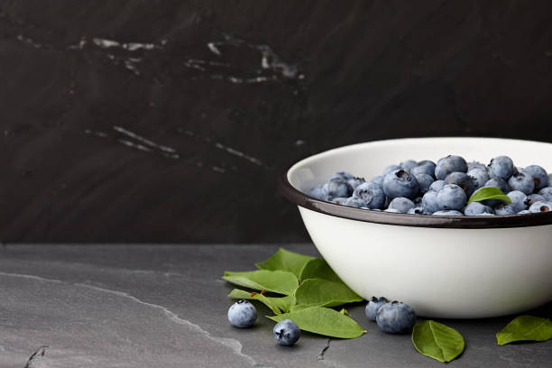 istock Fresh blueberries bowl on black stone countertop 821668776
