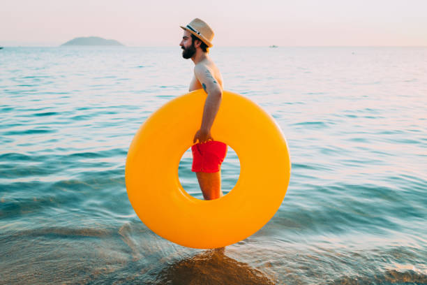 istock Handsome bearded man with a hat enjoying sunny summer day by the sea 821672600