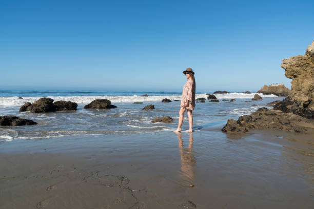 Woman Looks Out into the Sea A woman loos out into the Sea on a beautiful sunny day. rock sea malibu silhouette stock pictures, royalty-free photos & images