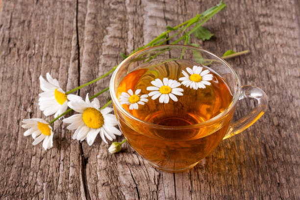 istock Herbal tea with fresh chamomile flowers on old wooden background 821691284