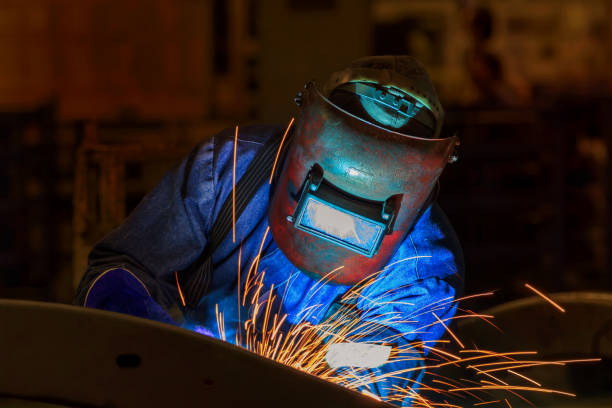 Worker at the factory is welding assembly automotive part Worker at the factory is welding assembly automotive part welding mask stock pictures, royalty-free photos & images