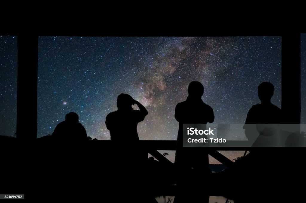 Silhouette of a photographers group who shoots the Landscape of Milky way over reservoir with mountain and deep forest at night sky Astronomy Stock Photo