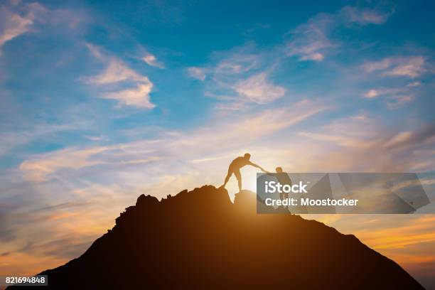 Silhouette Of Couple Teamwork Hiker Helping Each Other On Top Of Mountain Stock Photo - Download Image Now