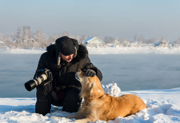 istock photographer with a dog sit in the snow 821719870