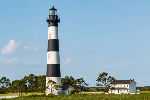 Forest of Cedar Trees Surrounds Bodie Island Lighthouse A forest of cedar trees surrounds the Bodie Island lighthouse and adjacent buildings on the Outer Banks of North Carolina near Nags Head. bodie island stock pictures, royalty-free photos & images