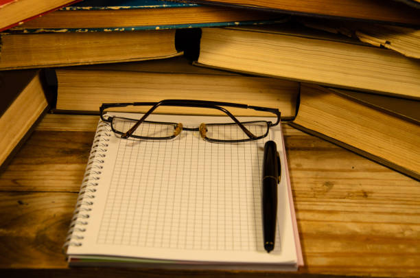 istock Notepad, fountain pen and glasses in front of books 821720184