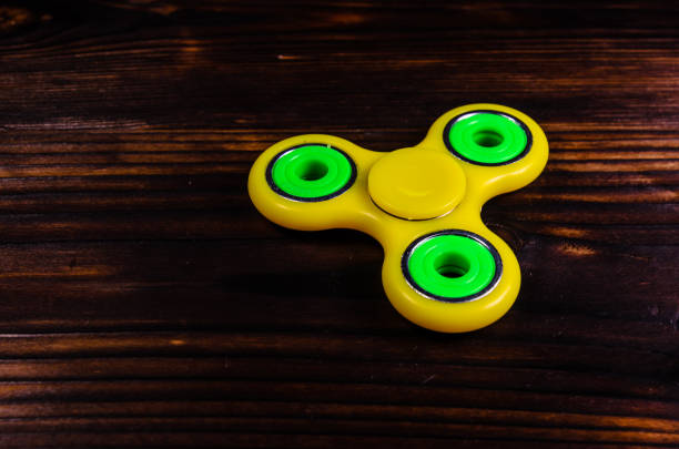 istock Yellow fidget spinner on wooden desk 821722932